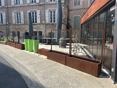 un immeuble doté d'une façade vitrée et d'une clôture métallique donnant sur le trottoir