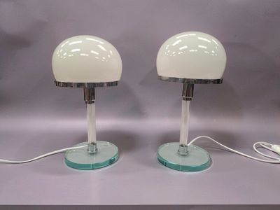 une paire de lampes de table en verre blanc avec des pieds transparents et un cordon blanc