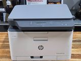 a printer sitting on top of a wooden table in front of a shelf