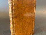 an old book with a brown cover sitting on top of a table