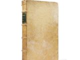 an old book with a green cover sitting on a white surface