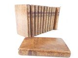 several old books are stacked on top of each other on a white surface