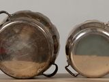 pair of silver plated pots with handles on a wooden table
