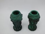 pair of green vases with faces on them sitting on a white surface