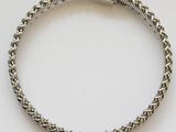 a close up of a silver bracelet with a red cord