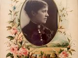 an old picture of a woman in a black dress with flowers around her neck
