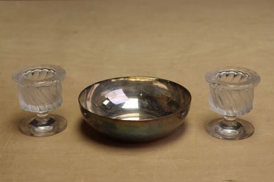 un bol en argent et deux verres posés sur une table