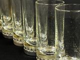 six verres alignés les uns à côté des autres sur une surface noire