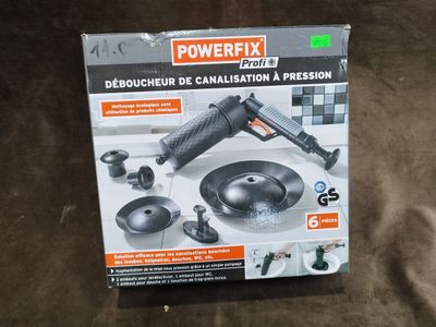 La boîte d'une perceuse Powerfix est posée sur une surface marron