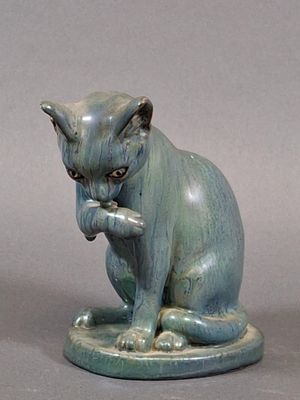 une statue représentant un chat assis sur une assiette