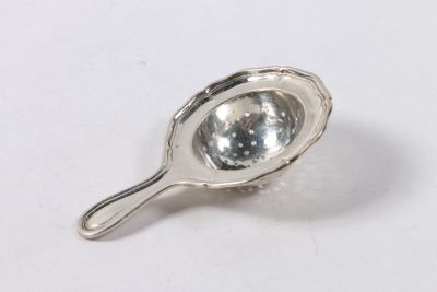 une cuillère en argent posée sur une surface blanche