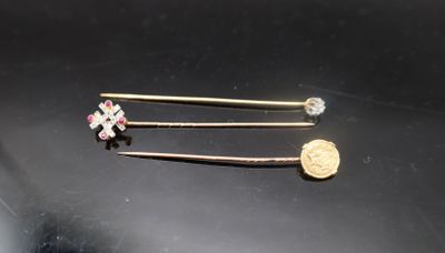 deux épingles sur un fond noir avec une pièce d'or