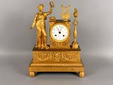 a gold clock sitting on a table with a key in front of it