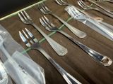many forks and spoons laid out on a table