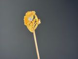 a close up of a yellow flower on a stick against a dark background