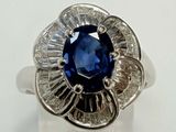 une photo d'une bague en forme de fleur, sertie d'un saphir bleu et de diamants