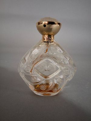 une petite bouteille en verre avec un bouchon doré, posée sur une table
