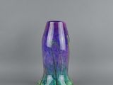 a purple and green vase sitting on top of a table