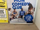 a sign that says mon comedy club next to a sign with a picture of a group of people