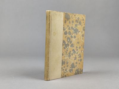 un vieux livre posé sur une table blanche à côté d'un mur gris
