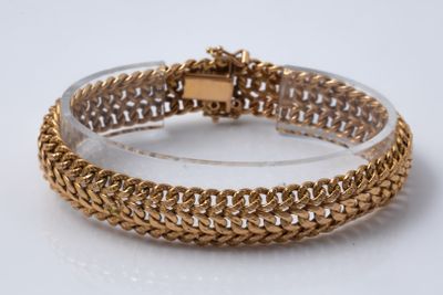 gros plan d'un bracelet en or sur une surface blanche