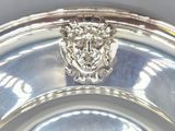 a silver plate with a lion head on top of it
