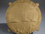 an image of a gold plate with a picture of a ship on it