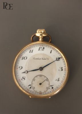 un gros plan d'une montre de poche en or posée sur une table