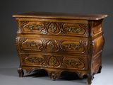 une commode ancienne ornée de sculptures raffinées sur le dessus