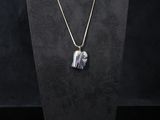a black and white necklace with a silver heart pendant on a black mannequin