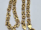 a close up of a gold chain on a white surface
