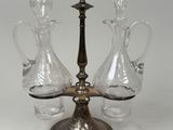 three glass decanters on a metal stand with a white background