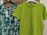 two green and white shirts hanging on a rack in a store
