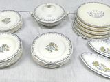 many plates and bowls on a table with a white table cloth