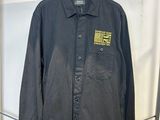 une veste de travail noire suspendue à un cintre dans un magasin de vêtements