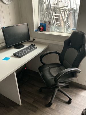 a desk with a computer and a chair in front of a window