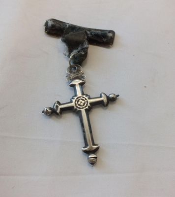 une croix en argent ornée d'un oiseau, posée sur une table blanche