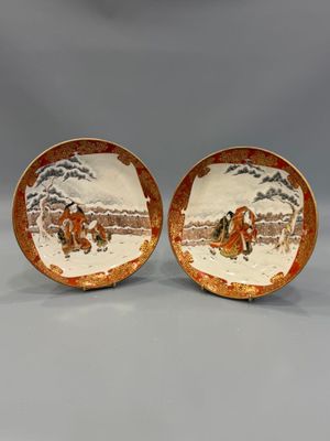 pair of chinese porcelain plates with figures on them on a gray background