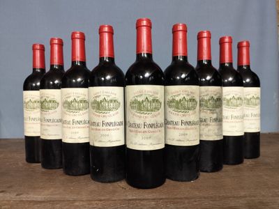 six bottles of red wine lined up on a wooden table