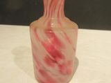 a pink and white vase sitting on a white table