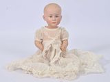 a baby doll sitting on a white surface with a white background