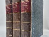 trois vieux livres posés l'un sur l'autre sur une surface blanche