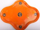 une assiette orange percée de trous posée sur un fond blanc