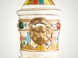 a white vase with a gold lion head on top of it