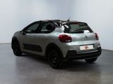 the back of a silver car parked in a room with a white wall