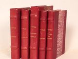 quatre livres rouges sont empilés les uns sur les autres sur une surface blanche