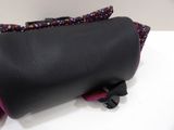 a black purse with a pink handle on a white table