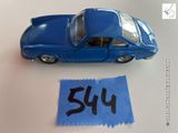 une petite voiture bleue à côté d'un bout de papier sur lequel est écrit « sh »