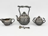 three pieces of silverware including a teapot, sugar bowl, and spoon
