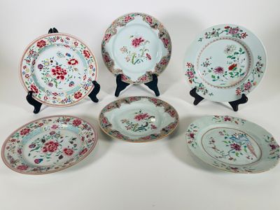 six assiettes ornées de motifs floraux, posées sur une surface blanche